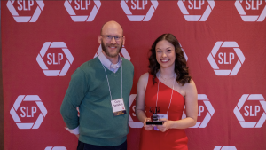 A man and a woman in front of a red backdrop.